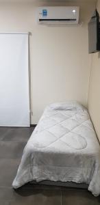 Cama blanca en habitación con pared blanca en Dpto Falucho en San Luis