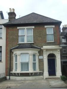 a red brick house with a large window at Cedars House Hotel in Croydon