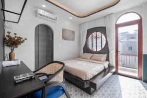 a bedroom with a bed and a table and a window at Nhà Bà Tư Boutique Homestay in Vung Tau