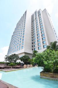 a large building with a swimming pool in front of it at Century Park Hotel - SHA Extra Plus in Bangkok