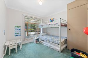 a bedroom with two bunk beds and a desk at 28 Nioka Street in Dalmeny