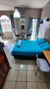Schlafzimmer mit einem blauen Bett, einem Tisch und Stühlen in der Unterkunft Encantador Apartamento Equipado in Tegucigalpa