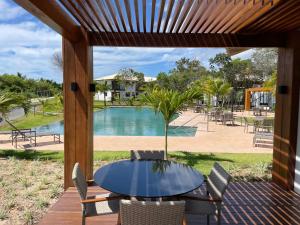 eine Terrasse mit einem Tisch, Stühlen und einem Pool in der Unterkunft Apartamento Praia do Forte in Mata de Sao Joao