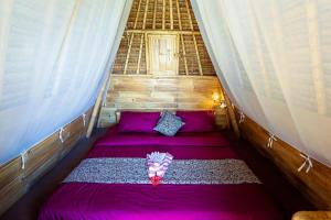 un piccolo letto in una camera con lenzuola viola di Taman Asta Gangga by ecommerceloka a Silebeng