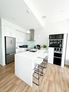 a white kitchen with a white counter and stools at Luxury 2 Bedroom Apartment with cocktail bar and espresso machine in Auckland