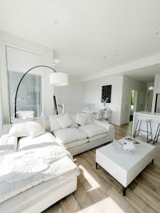 a white living room with a white couch and a table at Luxury 2 Bedroom Apartment with cocktail bar and espresso machine in Auckland