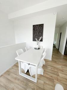 a white dining room table with white chairs at Luxury 2 Bedroom Apartment with cocktail bar and espresso machine in Auckland
