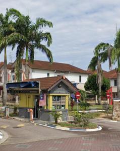 un bâtiment jaune dans une rue bordée de palmiers dans l'établissement JB Austin Perdana Homestay@Simple Comfy For 11pax, à Johor Bahru