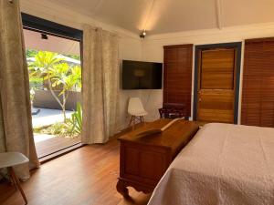 Schlafzimmer mit einem Bett, einem TV und einem Balkon in der Unterkunft Luxury & Tropical Villa Te Nunoa, Haapiti Moorea in Haapiti