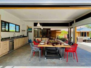 uma cozinha com uma mesa de madeira e cadeiras vermelhas em Luxury & Tropical Villa Te Nunoa, Haapiti Moorea em Haapiti