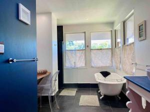 een badkamer met een bad, een wastafel en ramen bij Luxury & Tropical Villa Te Nunoa, Haapiti Moorea in Haapiti
