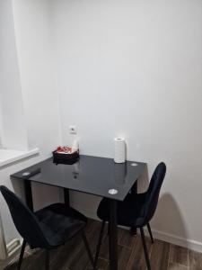 Un escritorio negro con dos sillas y una vela. en Stail en Bălţi