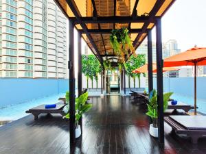 ein Pool mit Tischen und Sonnenschirmen in einem Gebäude in der Unterkunft Citrus Sukhumvit 13 Nana Bangkok by Compass Hospitality in Bangkok