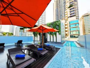 a pool with tables and umbrellas and a swimming pool at Citrus Sukhumvit 13 Nana Bangkok by Compass Hospitality - Newly Renovated in Bangkok