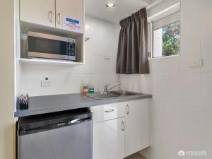 a small kitchen with a sink and a microwave at Studio 3 ENDEAVOUR INN in Emu Park