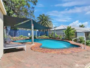 a swimming pool with a canopy over a brick patio at Studio 3 ENDEAVOUR INN in Emu Park