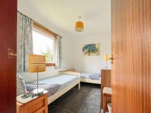 a bedroom with two beds and a window at Gean Cottage in Powmill