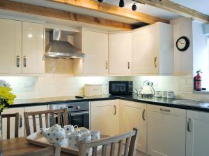 une cuisine avec des placards blancs et une table en bois dans l'établissement Crabapple Cottage, à Llanyblodwel
