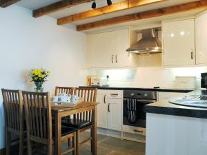 Il comprend une cuisine équipée d'une table, de chaises et d'une cuisinière. dans l'établissement Crabapple Cottage, à Llanyblodwel