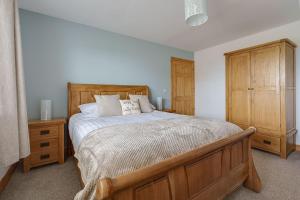 a bedroom with a large bed and a wooden cabinet at Ty Llewelyn in Twdweiliog