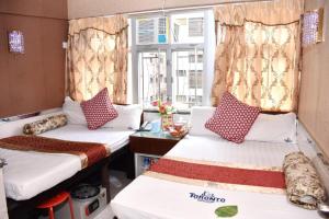 twee bedden in een kamer met een raam bij London Guest House in Hong Kong