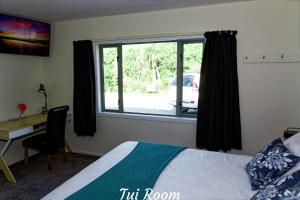 a bedroom with a bed and a desk and a window at Awatuna Sunset Lodge in Hokitika