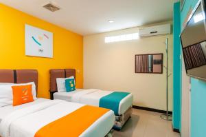 2 Betten in einem Zimmer mit gelben Wänden in der Unterkunft Sans Hotel Finest Medan in Medan