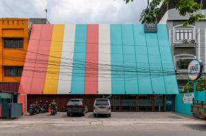 ein farbenfrohes Gebäude mit davor geparkt in der Unterkunft Sans Hotel Finest Medan in Medan