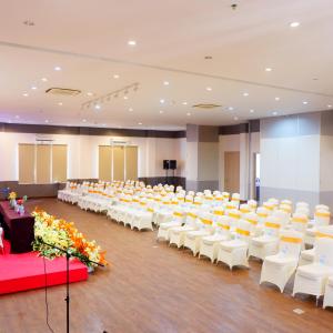 una sala de banquetes vacía con sillas y mesas blancas en Manise Hotel en Ambon
