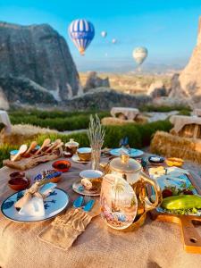 une table avec des plaques de nourriture et des ballons à air chaud dans l'établissement Wish Cappadocia, à Uçhisar