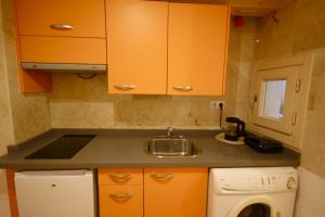 una pequeña cocina con armarios naranjas y fregadero en cervantes apartment, en Málaga