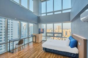 Schlafzimmer mit einem Bett, einem Schreibtisch und Fenstern in der Unterkunft Kolon Seacloud Hotel in Busan