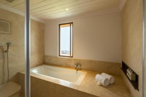 a bath tub in a bathroom with a window at ama Stays & Trails Puttabong Cottage, Darjeeling in Darjeeling
