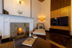 a living room with a fireplace and a tv at ama Stays & Trails Puttabong Cottage, Darjeeling in Darjeeling