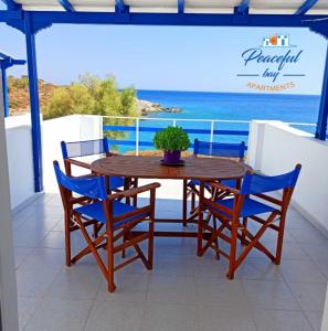 een houten tafel en stoelen op een balkon met uitzicht op de oceaan bij Peaceful Bay in Megas Gialos - Nites
