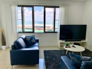 Serenity Deja Blue - at Darwin Waterfront في داروين: غرفة معيشة مع أريكة زرقاء وتلفزيون بشاشة مسطحة