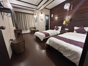 um quarto de hotel com duas camas e uma mesa em The Nettle and Fern Hotel Gangtok em Gangtok