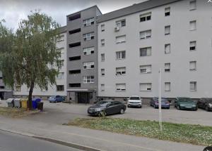duży biały budynek z samochodami zaparkowanymi na parkingu w obiekcie Studio apartman Mirta w mieście Varaždin