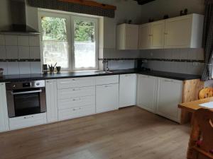 a kitchen with white cabinets and a wooden floor at Ferienhaus Kitting in Lembach