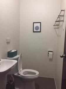 Łazienka z białą toaletą i umywalką w obiekcie Mactan Airport Guesthouse w mieście Cogon