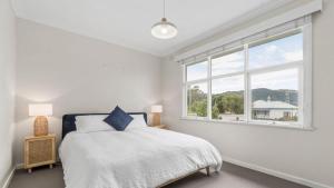 a white bedroom with a bed and a window at Nelson By The Bay in Apollo Bay