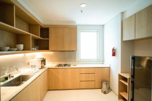 a kitchen with wooden cabinets and a window at Midtown Residence Surabaya in Surabaya