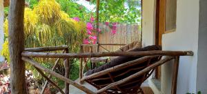 una sedia a dondolo in legno su una veranda con fiori di Morningstar Bungalows Zanzibar a Matemwe