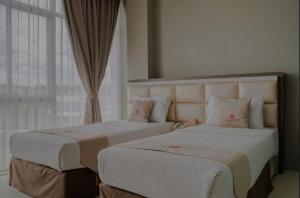 2 łóżka w pokoju hotelowym z oknem w obiekcie Osaka Hotel Batam w mieście Nagoja