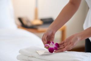 una mujer sosteniendo una flor púrpura en una cama en maejima Hotel en Naha