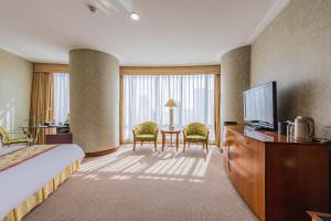 a hotel room with a bed and a flat screen tv at Hotel Nikko Dalian in Dalian