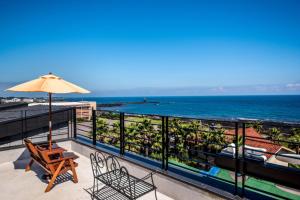 a balcony with a chair and an umbrella and the ocean at Sea and Wave in Seogwipo