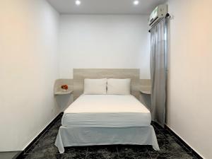 um quarto com uma cama num quarto branco em Pacific Coast Hotel em Playa Bonita Village