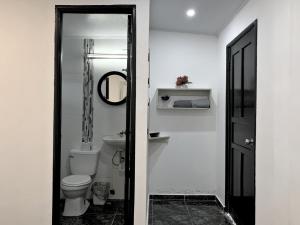 a white bathroom with a toilet and a mirror at Pacific Coast Hotel in Playa Bonita Village