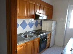 a kitchen with a stove, sink and refrigerator at Apartamentos Beni-Beach in Benidorm